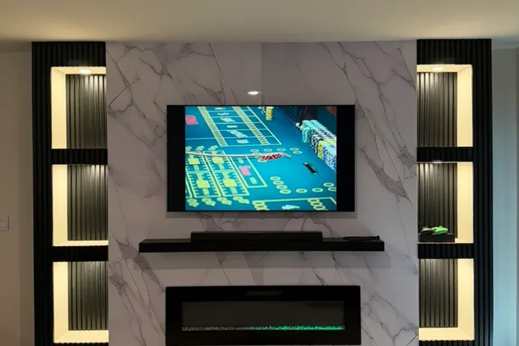 Finished custom media wall with marble-look tile, an electric fireplace and illuminated niches