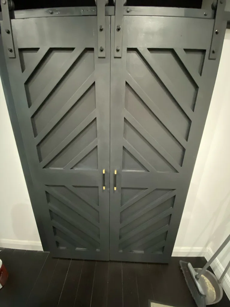 Custom charcoal barn doors with geometric trim and brass pulls