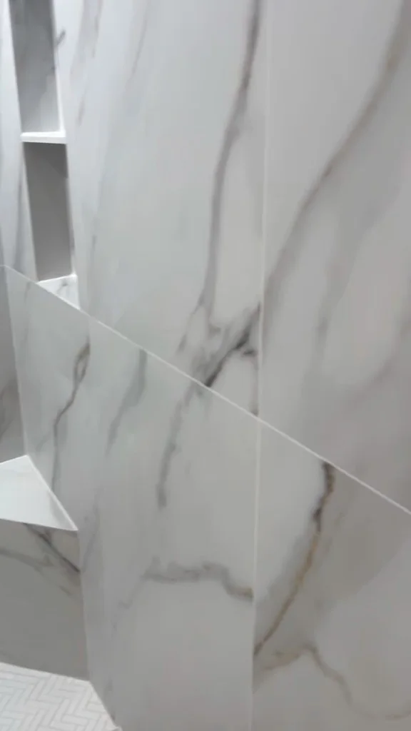 Marble-look tiled shower with two recessed storage niches