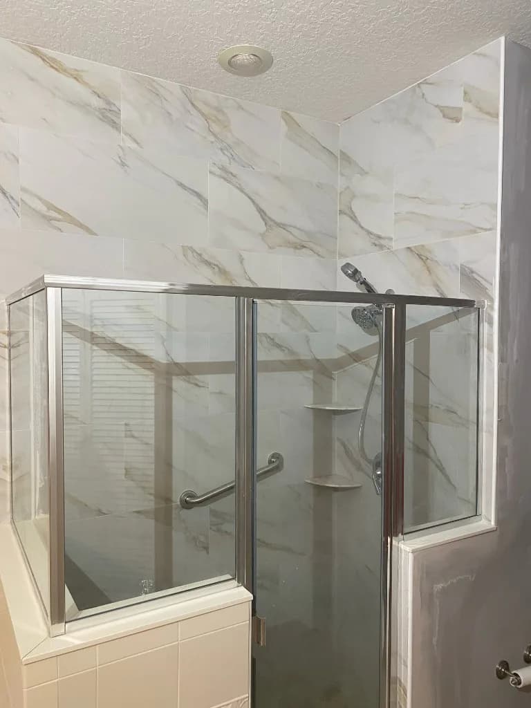 Finished marble-look shower with a stainless sliding glass enclosure