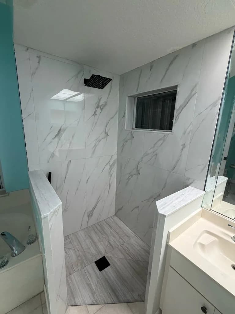 Tub area converted to a walk-in shower with marble-look tile and a black rain head